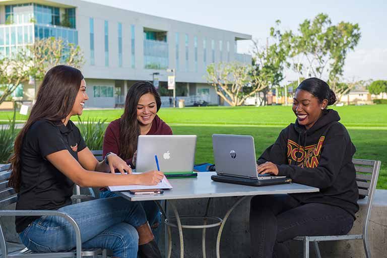 Three students study at a table outside at California State University Dominguez Hills.