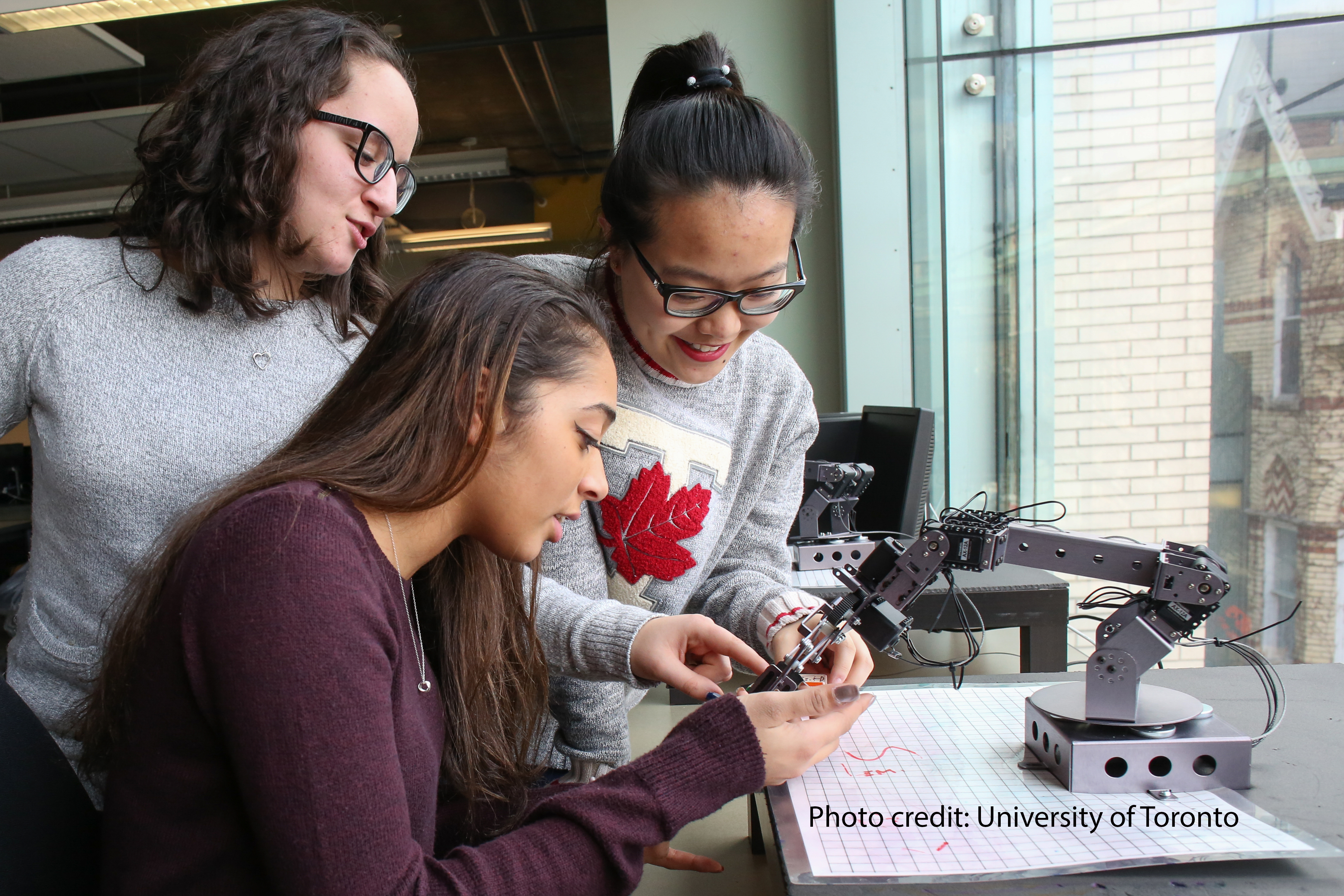 In the fall of 2016, the proportion of women in U of T's Faculty of Applied Science & Engineering's first-year class was 40.1 per cent, the highest figure among Ontario engineering programs at that time, according to statistics from the Council of Engineering Deans of Ontario. Pictured (left to right): Michela Trozzo, electrical & computer engineering student; Christian Pavlidis, civil engineering student; and Elisha Lu, electrical and computer engineering student work with a robotic arm.